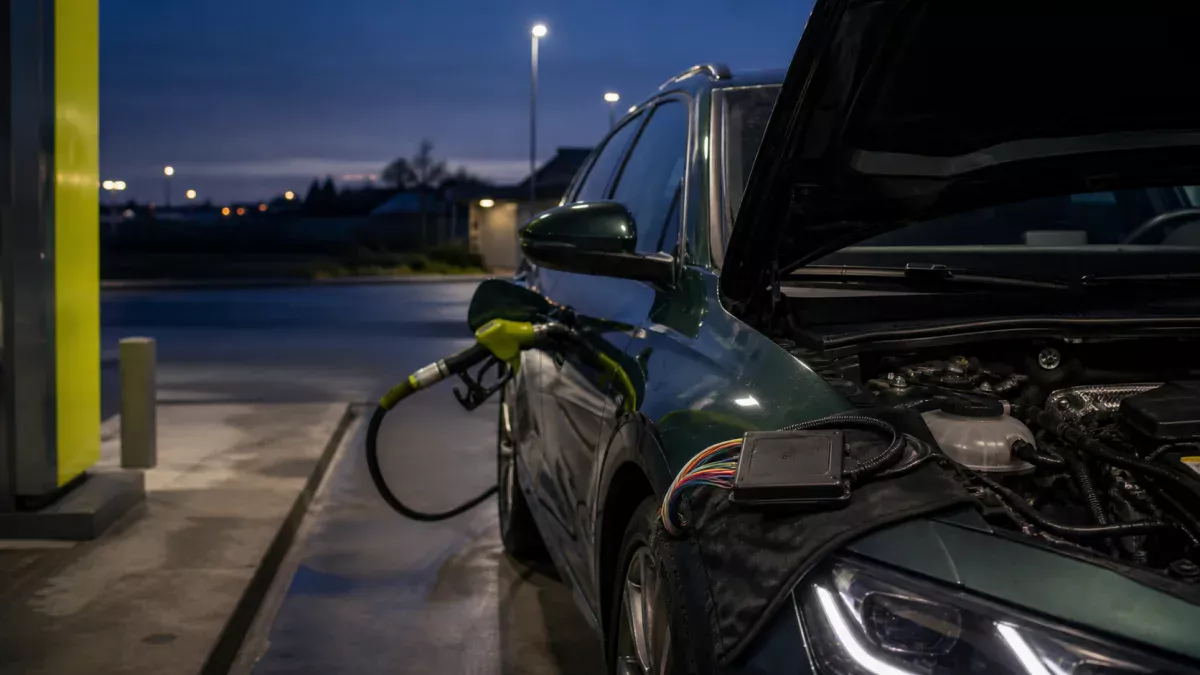 Voiture essence équipée d’un module E85 près d’une pompe de carburant
